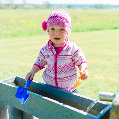 Zwei kleine Mädchen spielen mit einer Wasserpumpe