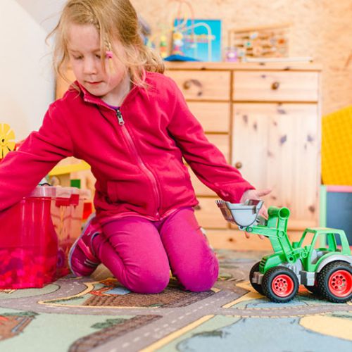 Mädchen spielt im Kinderzimmer mit einem Traktor