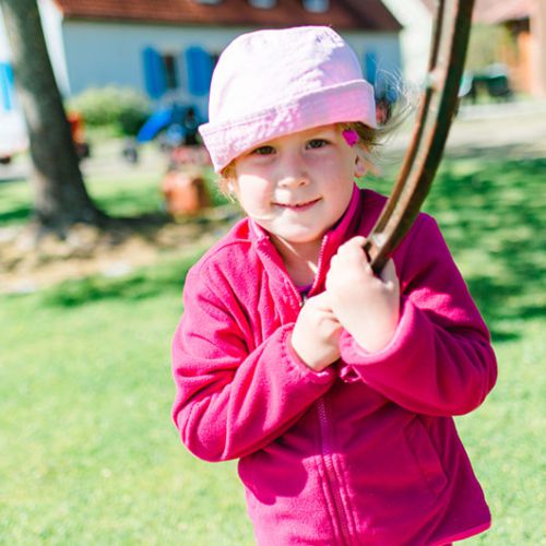 Kleines Mädchen spielt mit einer Wasserpumpe